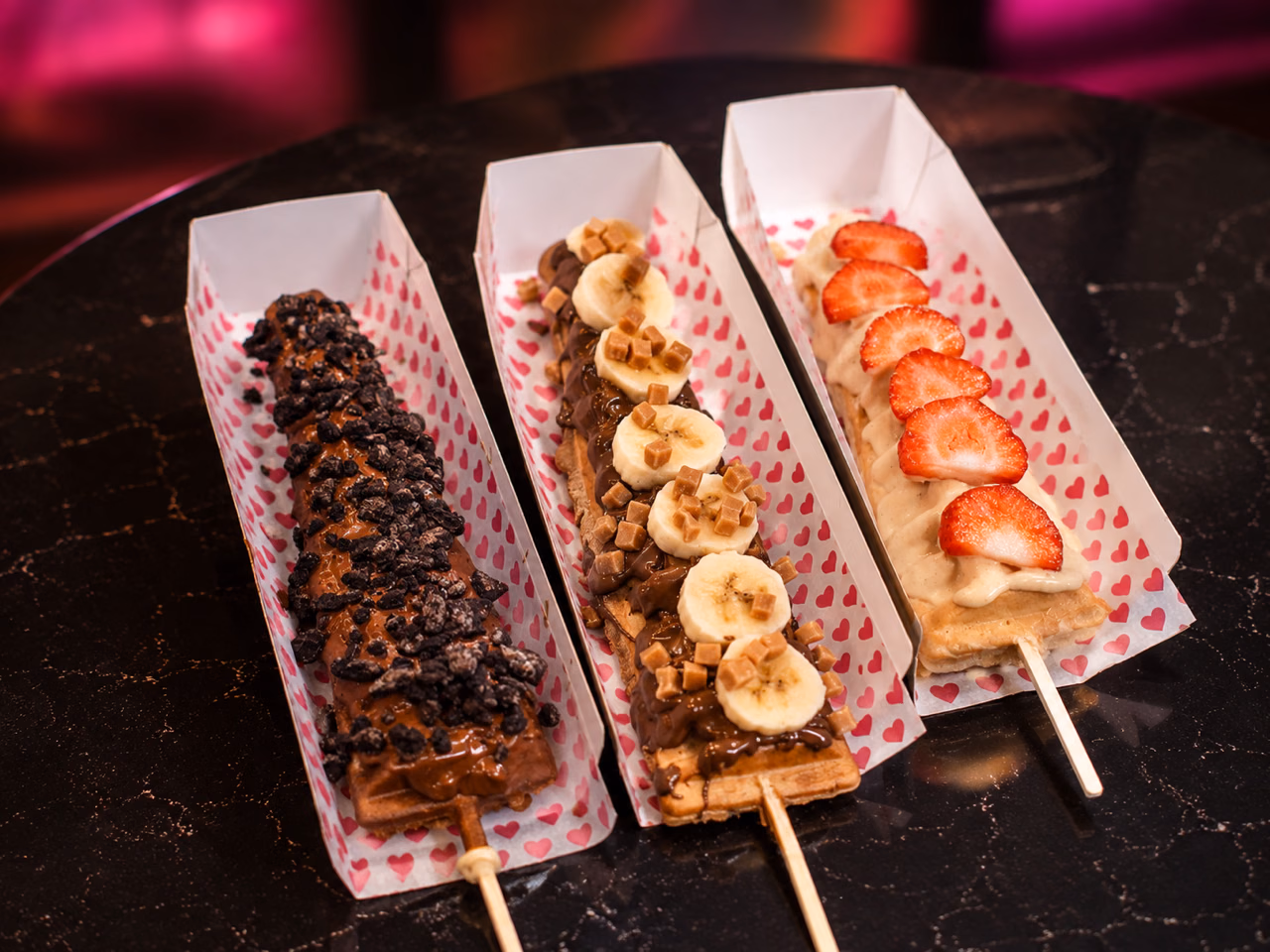 Three loaded waffle pops topped with chocolate crumb, banana and strawberries